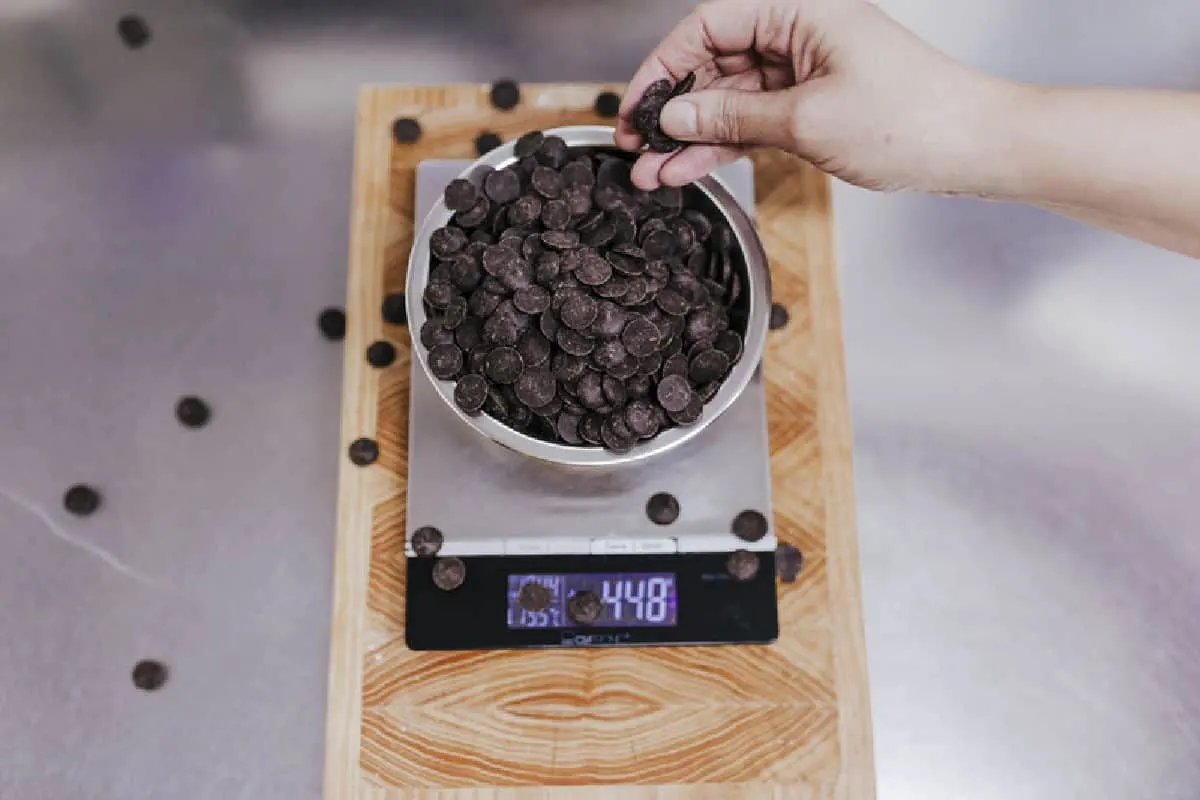 chocolate chips on a kitchen scale measuring grams in a cup