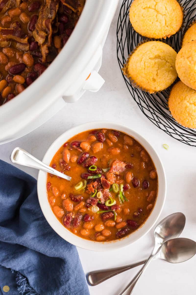 white bowl of baked beans and corn muffins