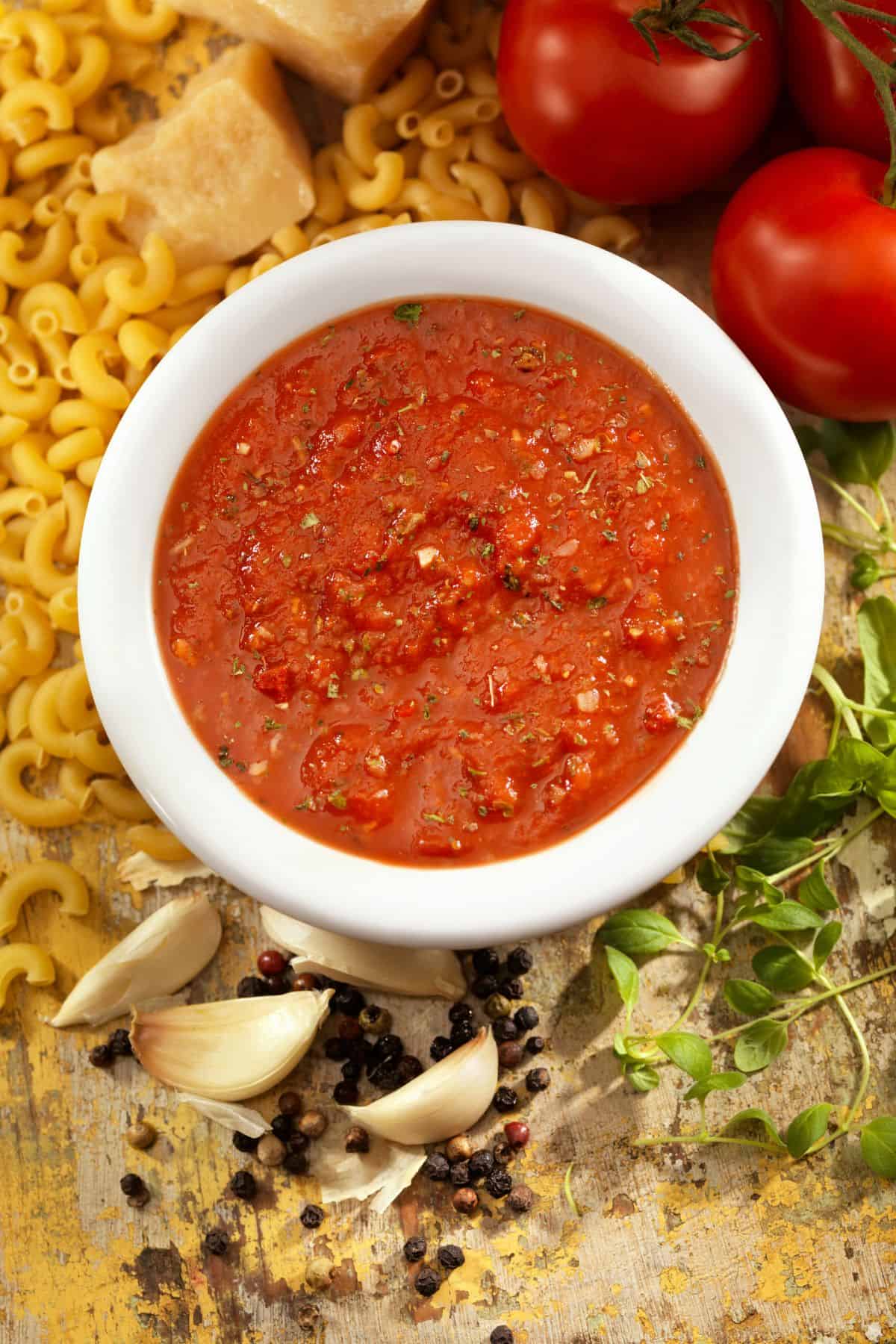 bowl of marinara sauce surrounded by pasta