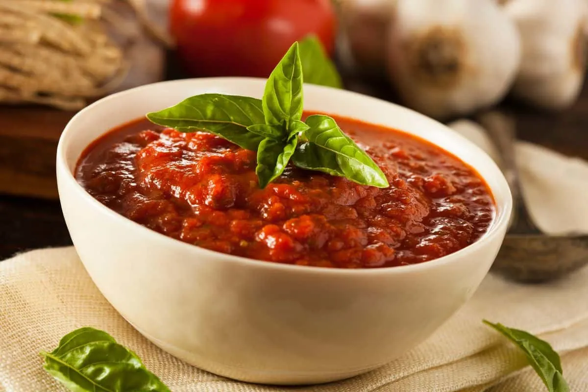 bowl of tomato sauce with basil on top