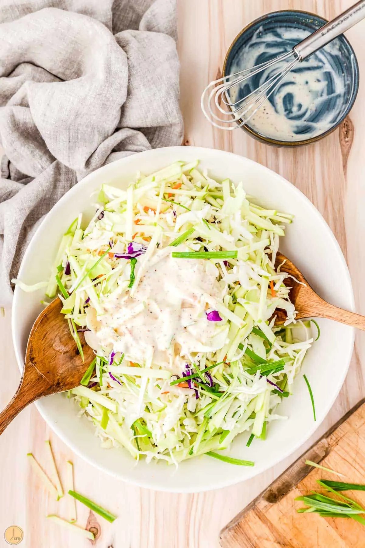 apple slaw with dressing being mixed in