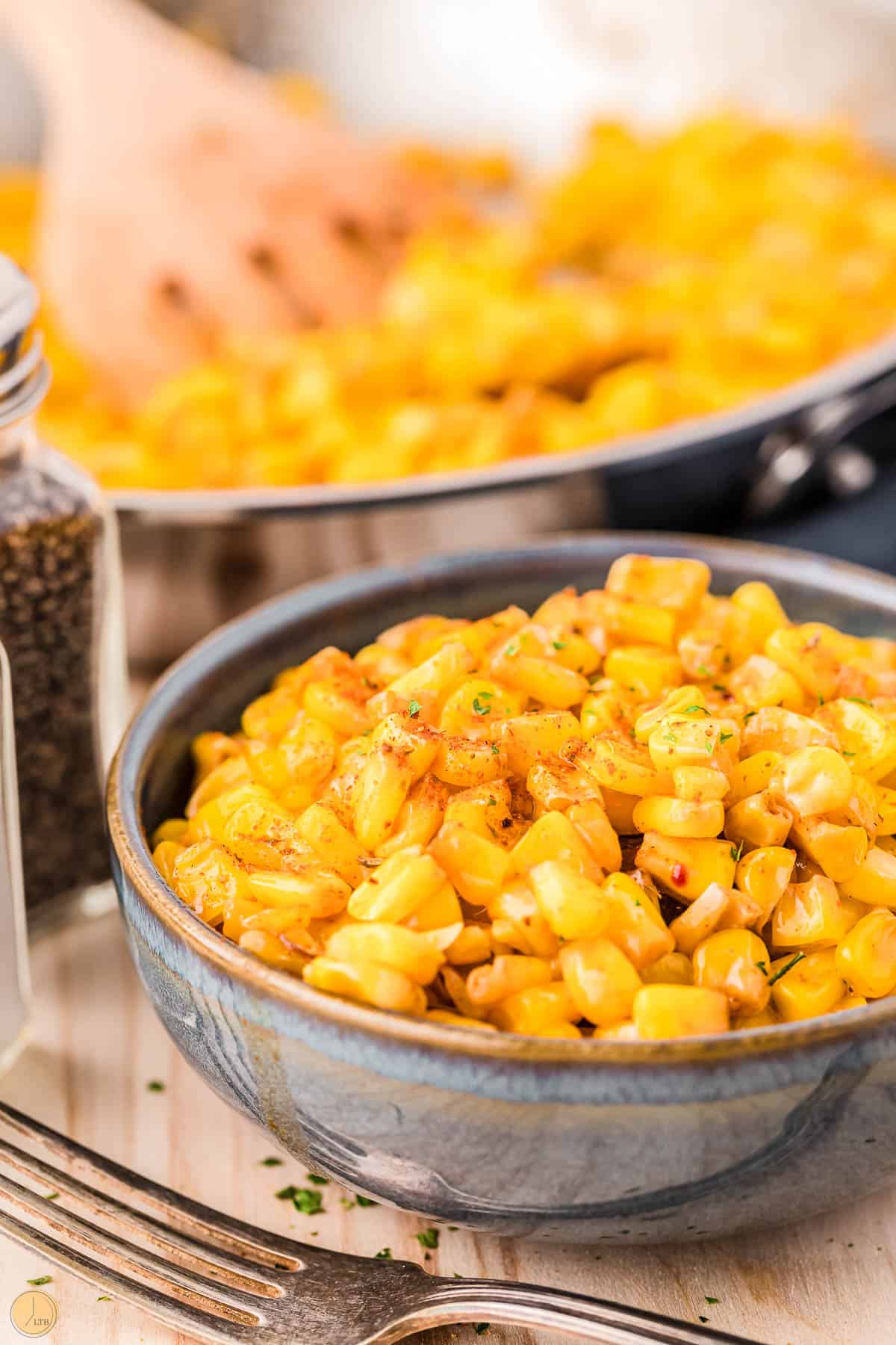 bowl of fried corn in front of a skillet