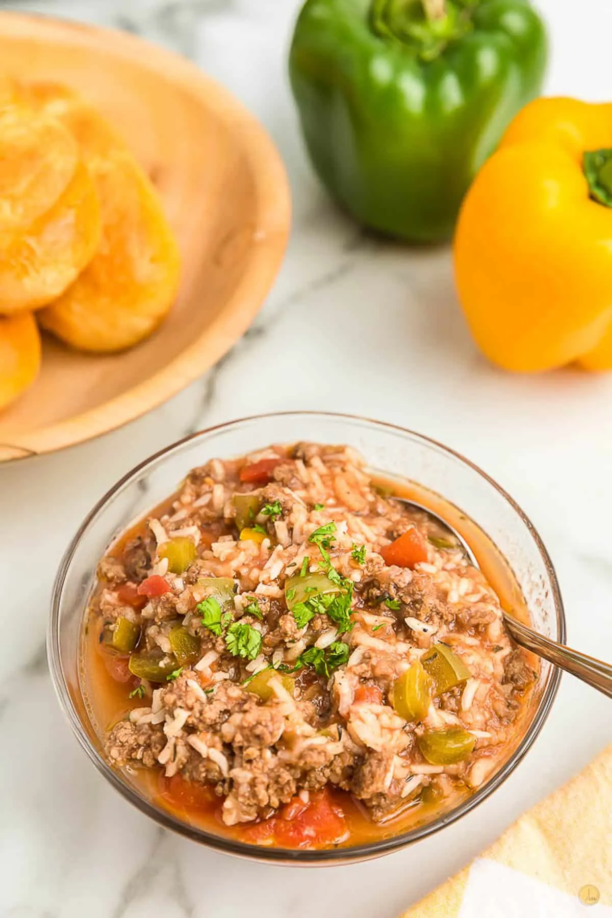 clear bowl of stuffed pepper soup with peppers in the background