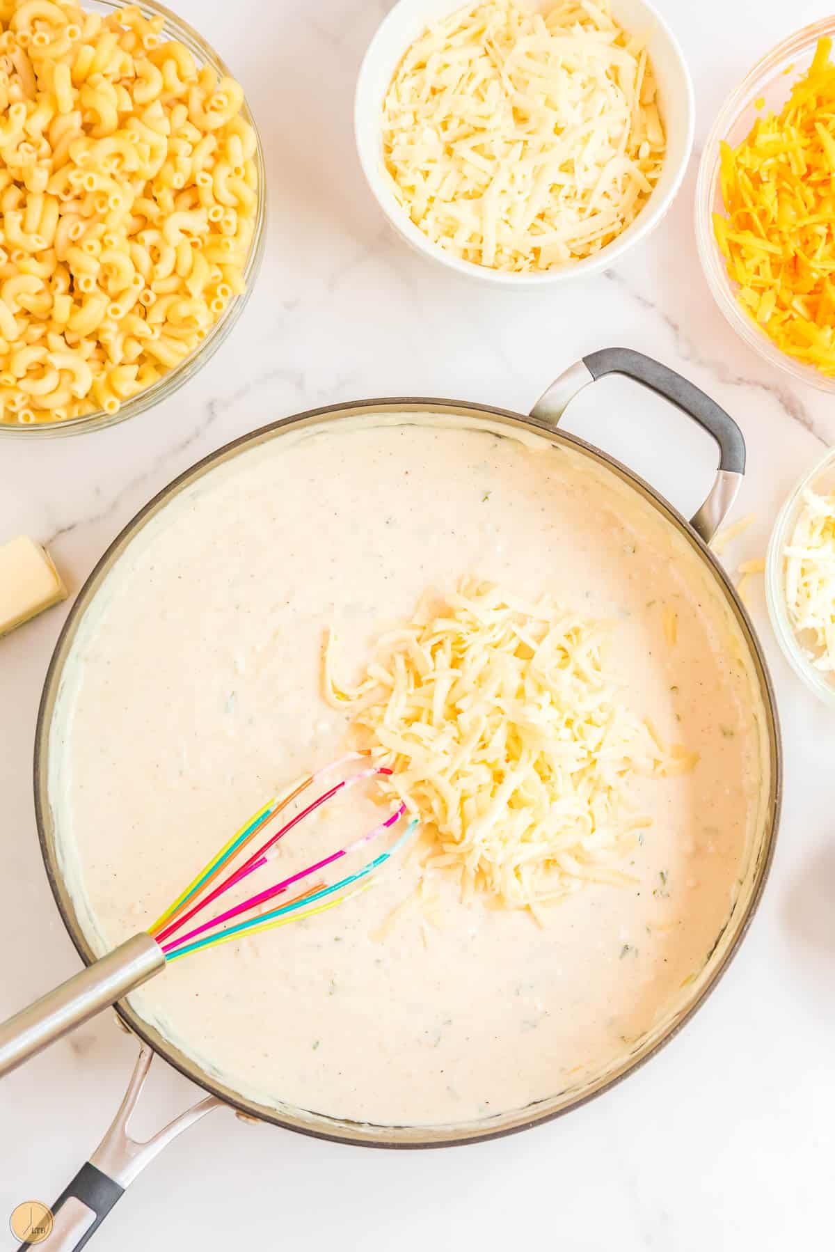 cheese mixing in a sauce in a pan with a whisk