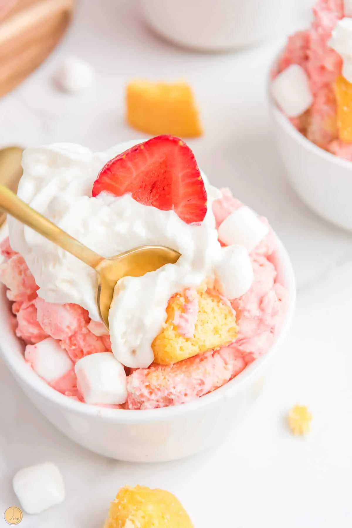 spoon scooping out marshmallows from a bowl with strawberries