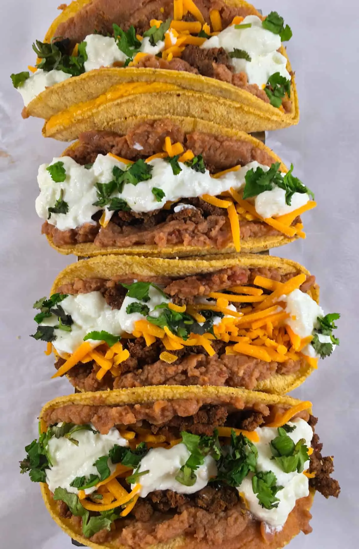 overhead picture of three tacos with cheese and beans