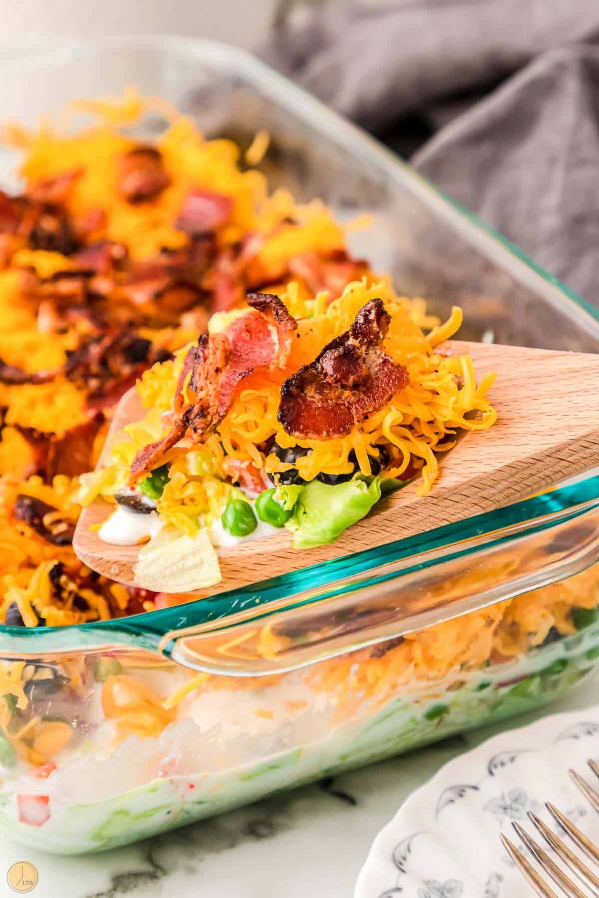 wood spoon with a scoop of salad and bacon on top as a crunchy salad topping