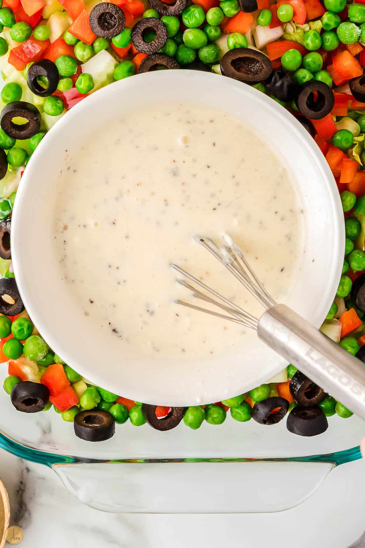 bowl of dressing with a silver whisk in a salad bowl