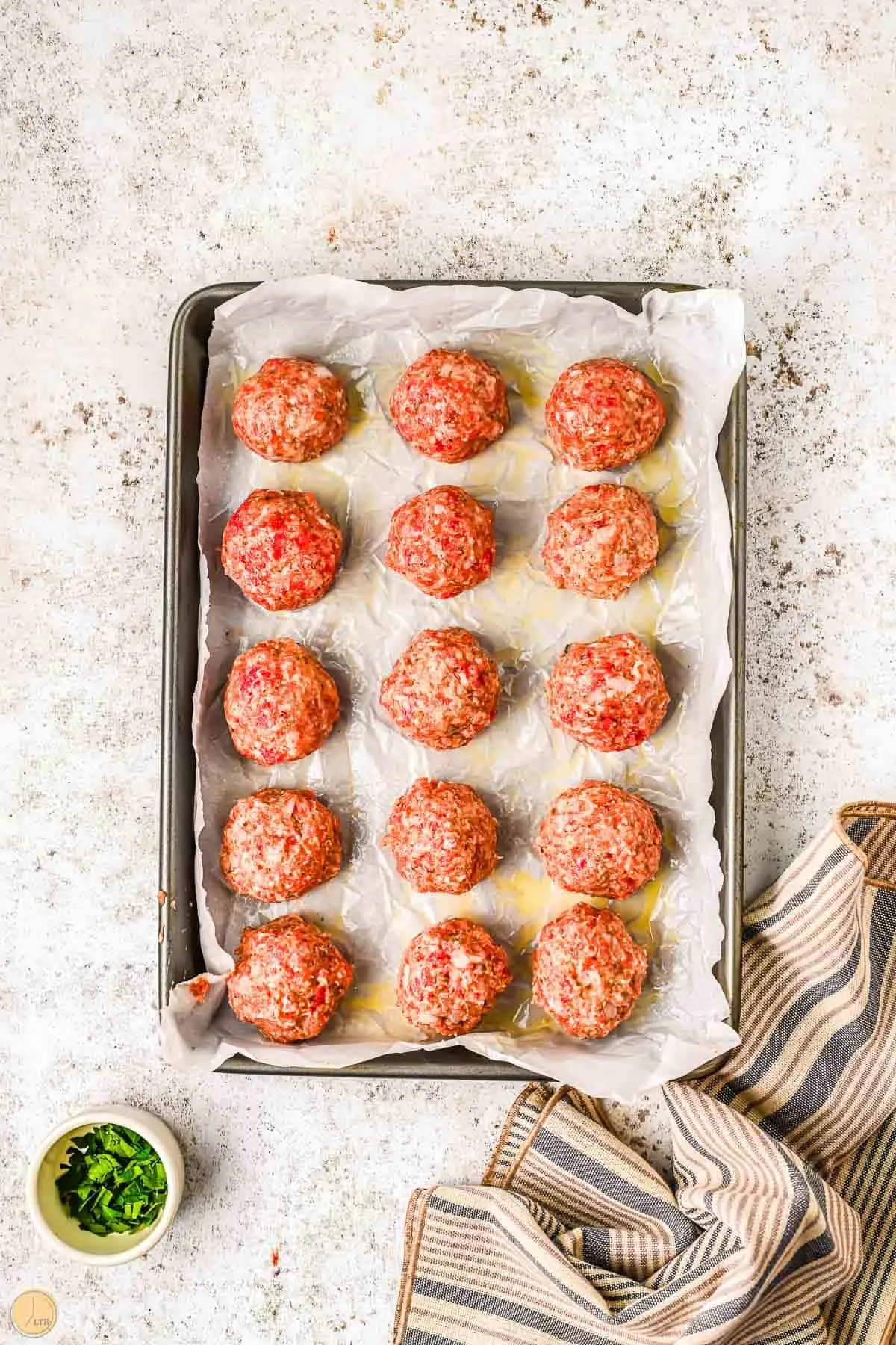 unbaked meatballs on a baking sheet with parchment paper