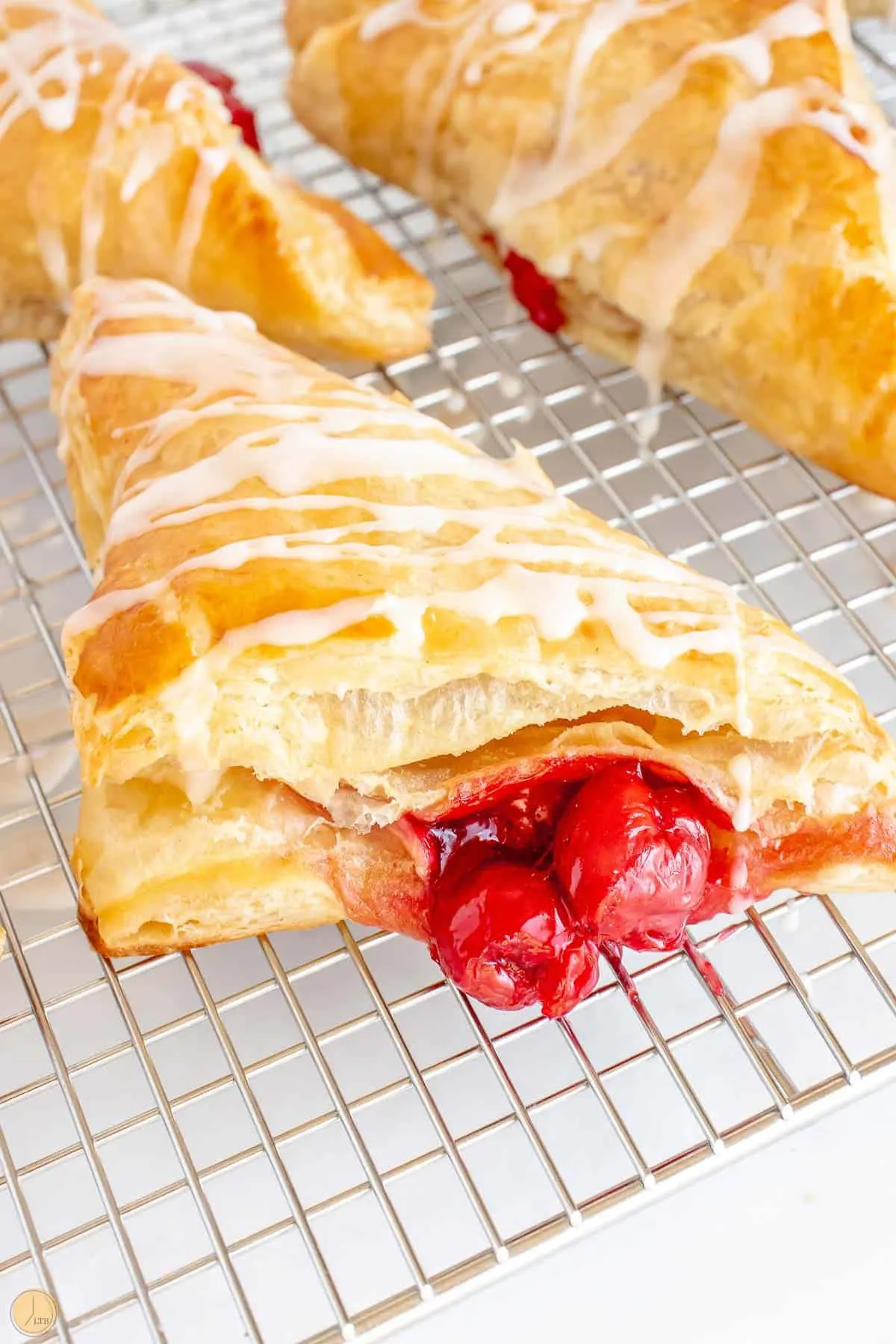 cherry turnovers on a wire rack with powdered sugar glaze