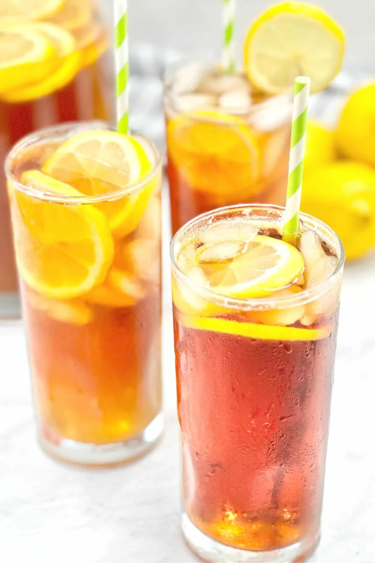 close up of glasses of iced tea with lemon slices and straws