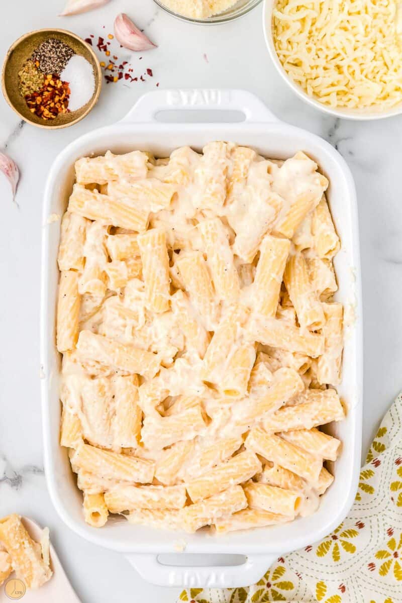 unbaked cheesy noodles in a white casserole dish