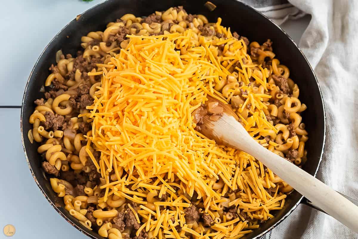 hamburger helper in a skillet with shredded cheese on top