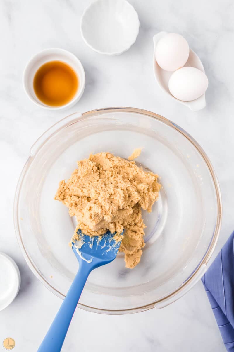 butter and brown sugar mixed in a clear bowl with a blue spatula