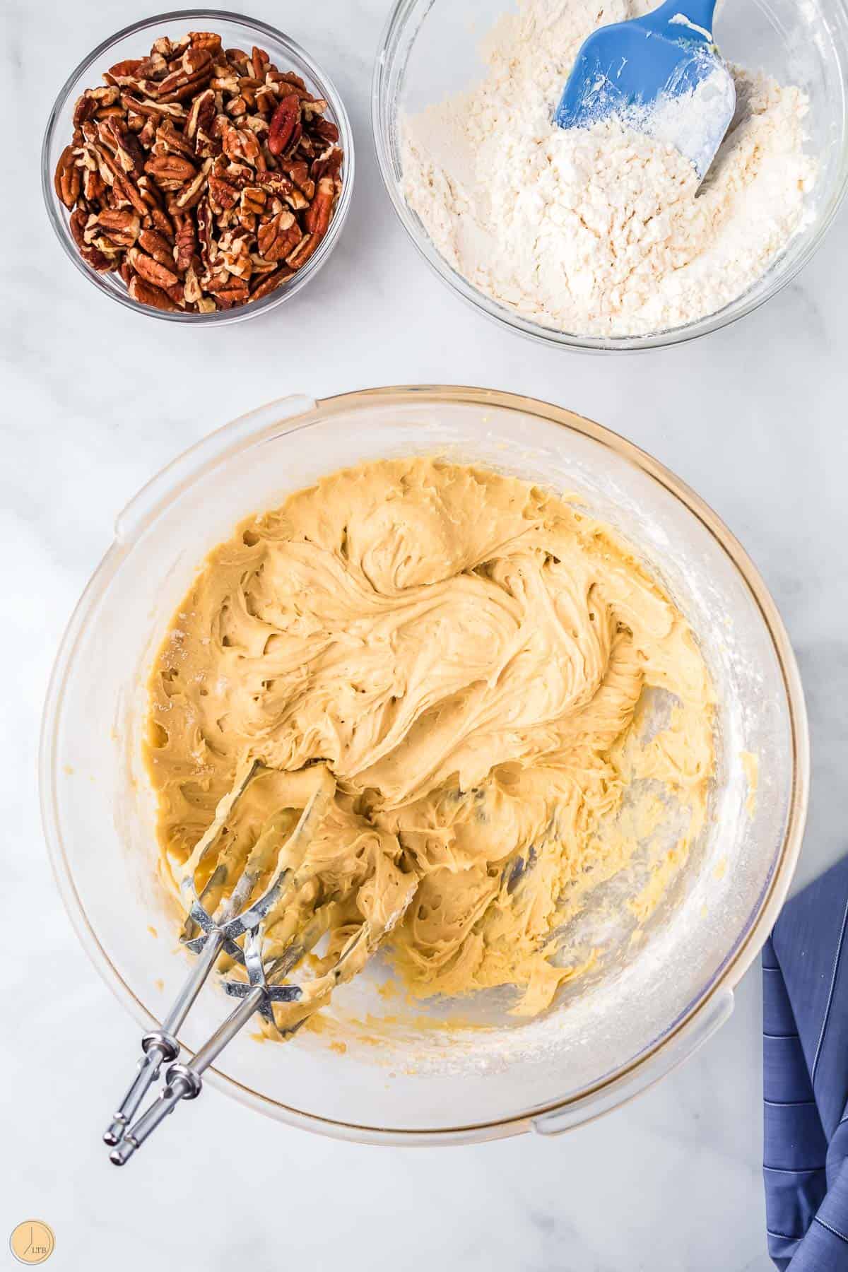 cookie dough in a clear bowl with beaters