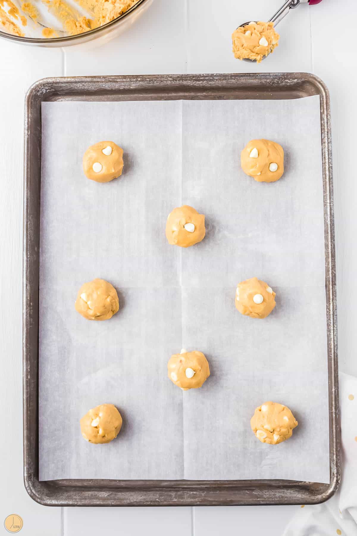 balls of cookie dough on a baking sheet with parchment paper