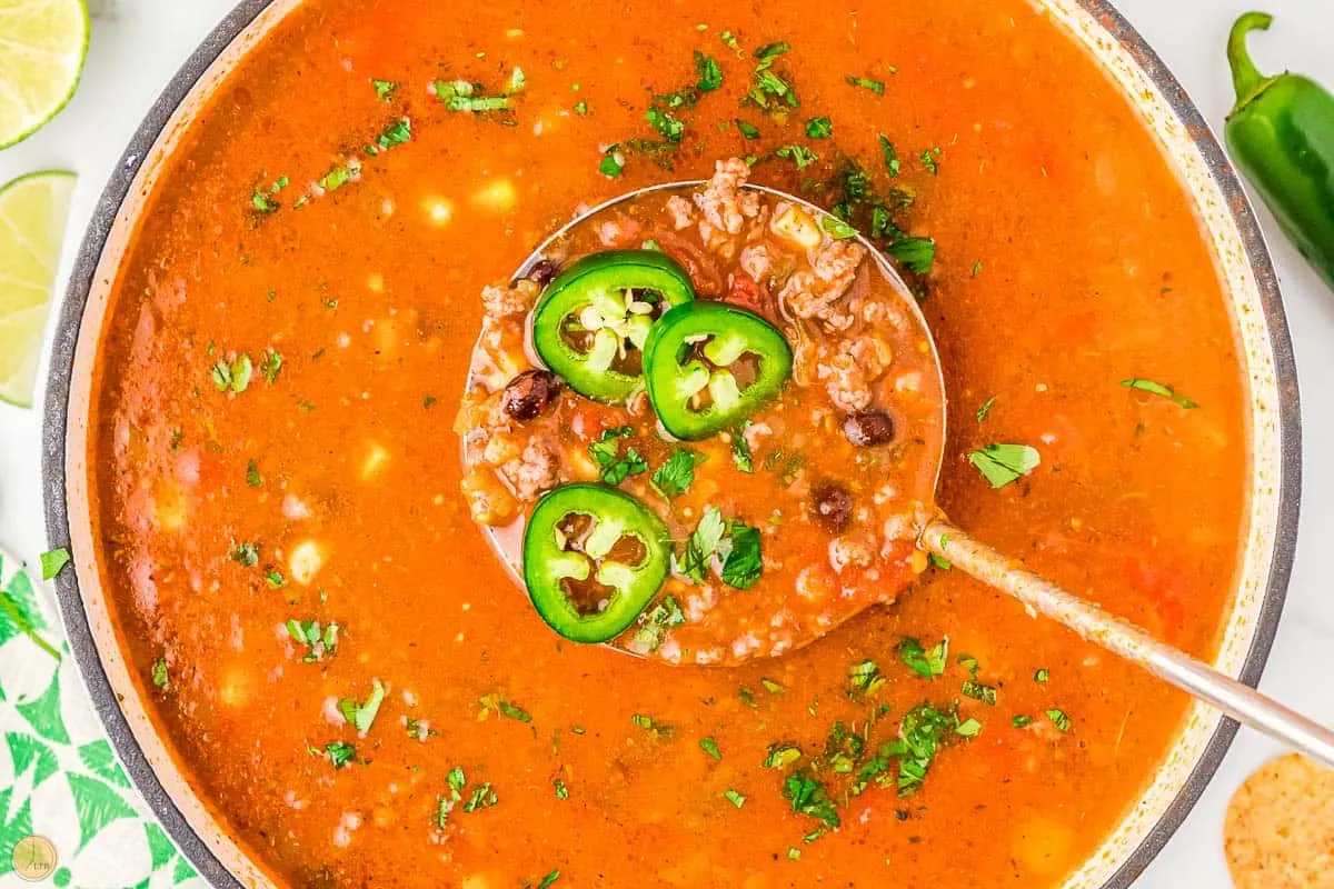ladle of 7 can taco soup with fresh jalapeno slices on it