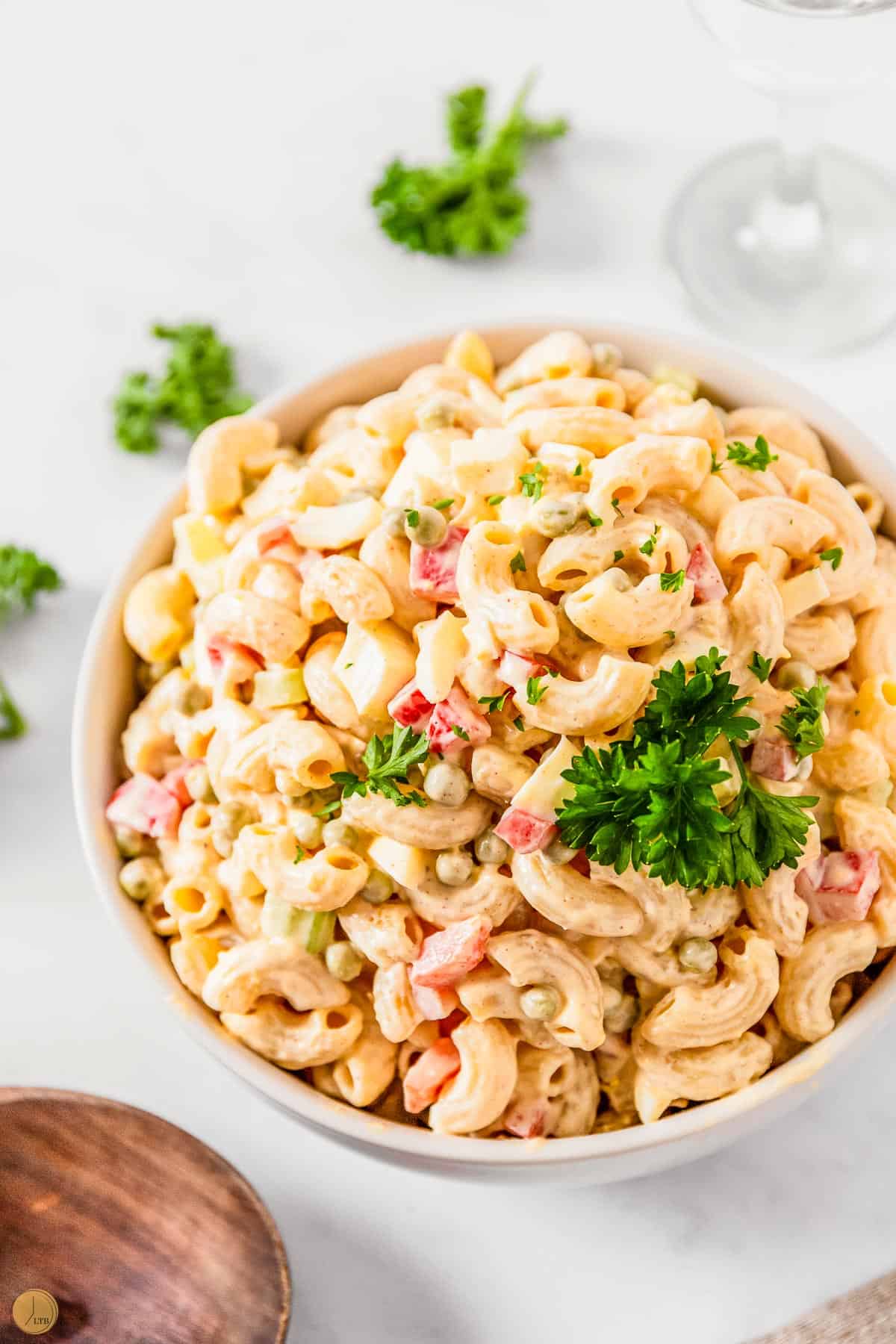bowl of elbow macaroni with vegetables and a wood spoon