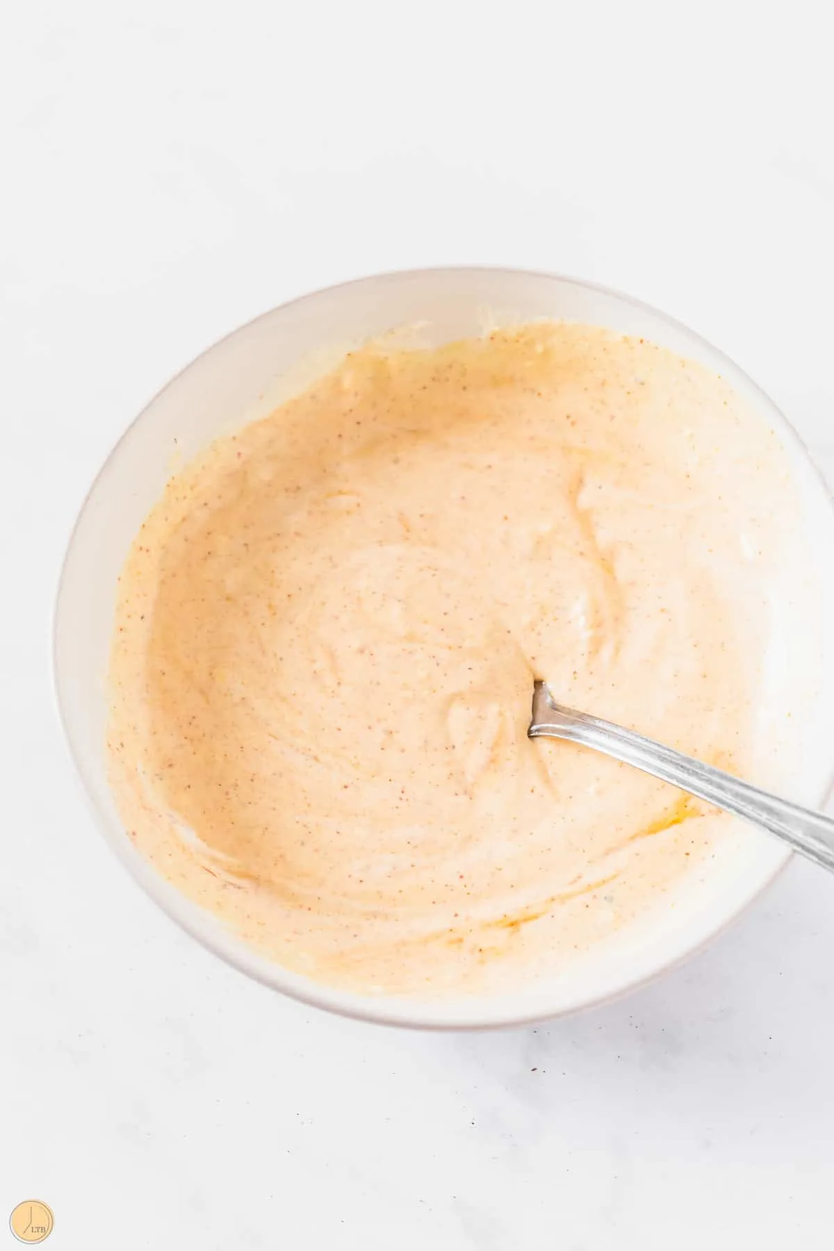 creamy mayonnaise dressing in a bowl with a spoon