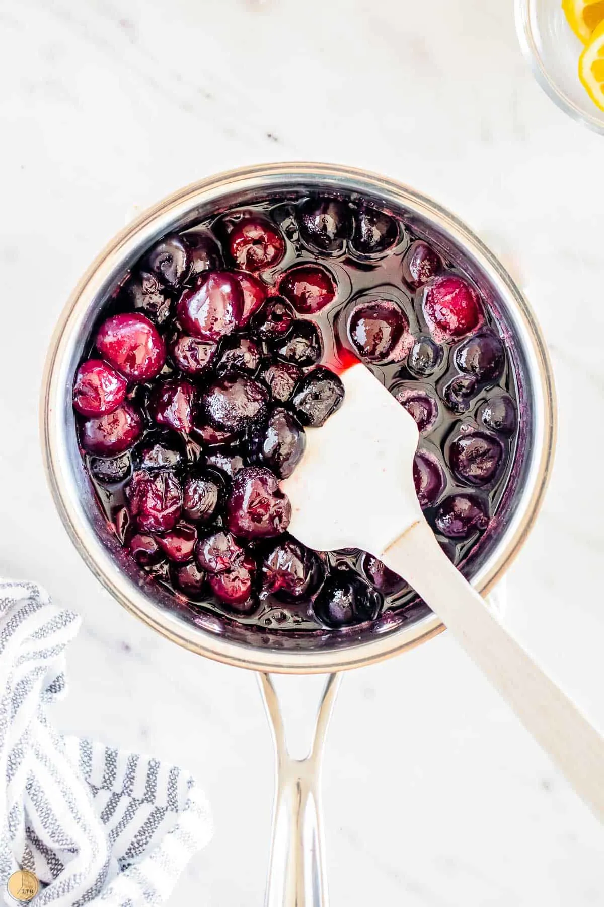 pitted cherries in a pot with a spatula