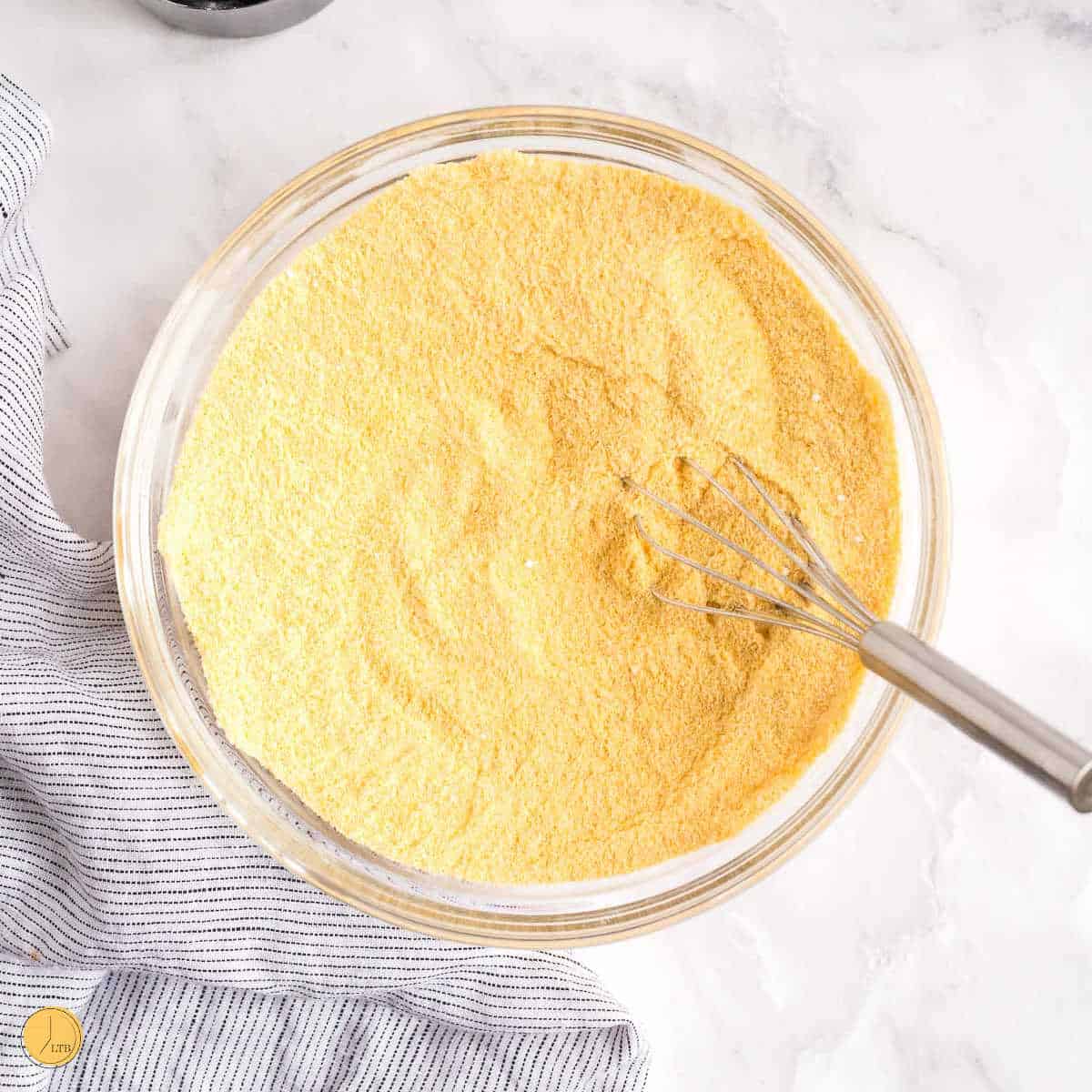overhead bowl of cornmeal with a whisk