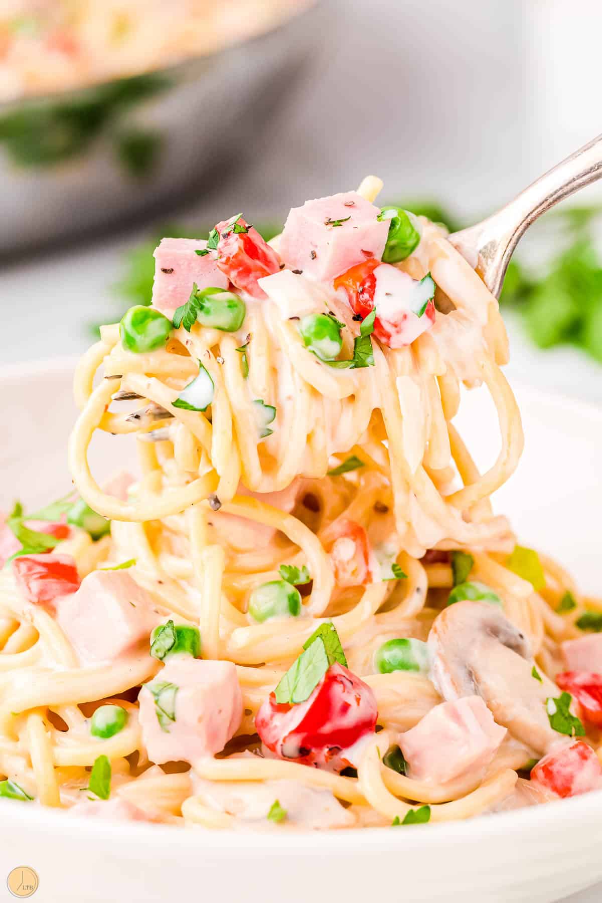 fork of spaghetti and ham with peas
