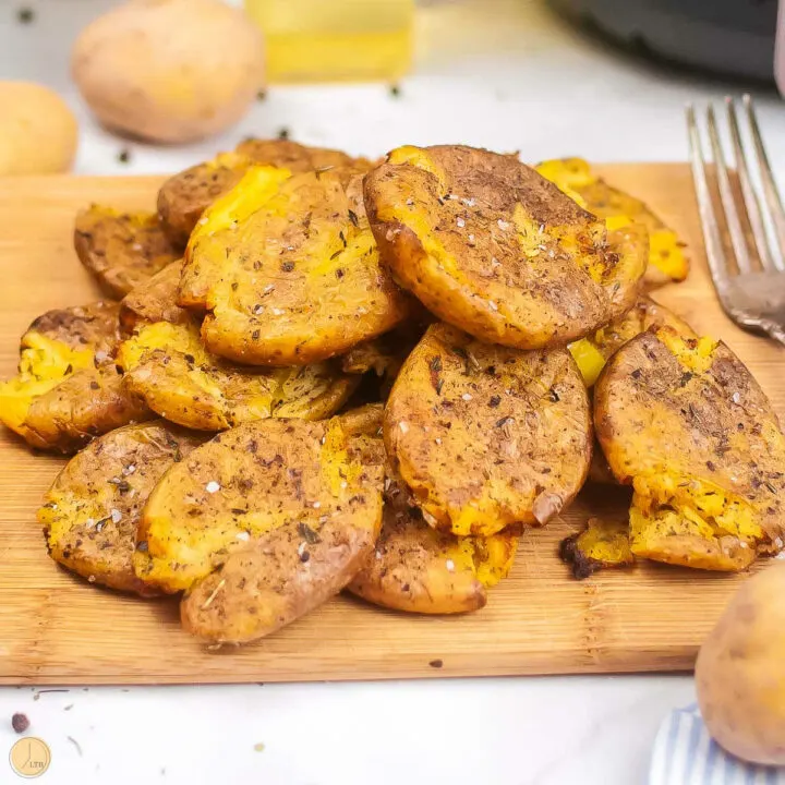 cutting board topped with air fryer smashed potatoes