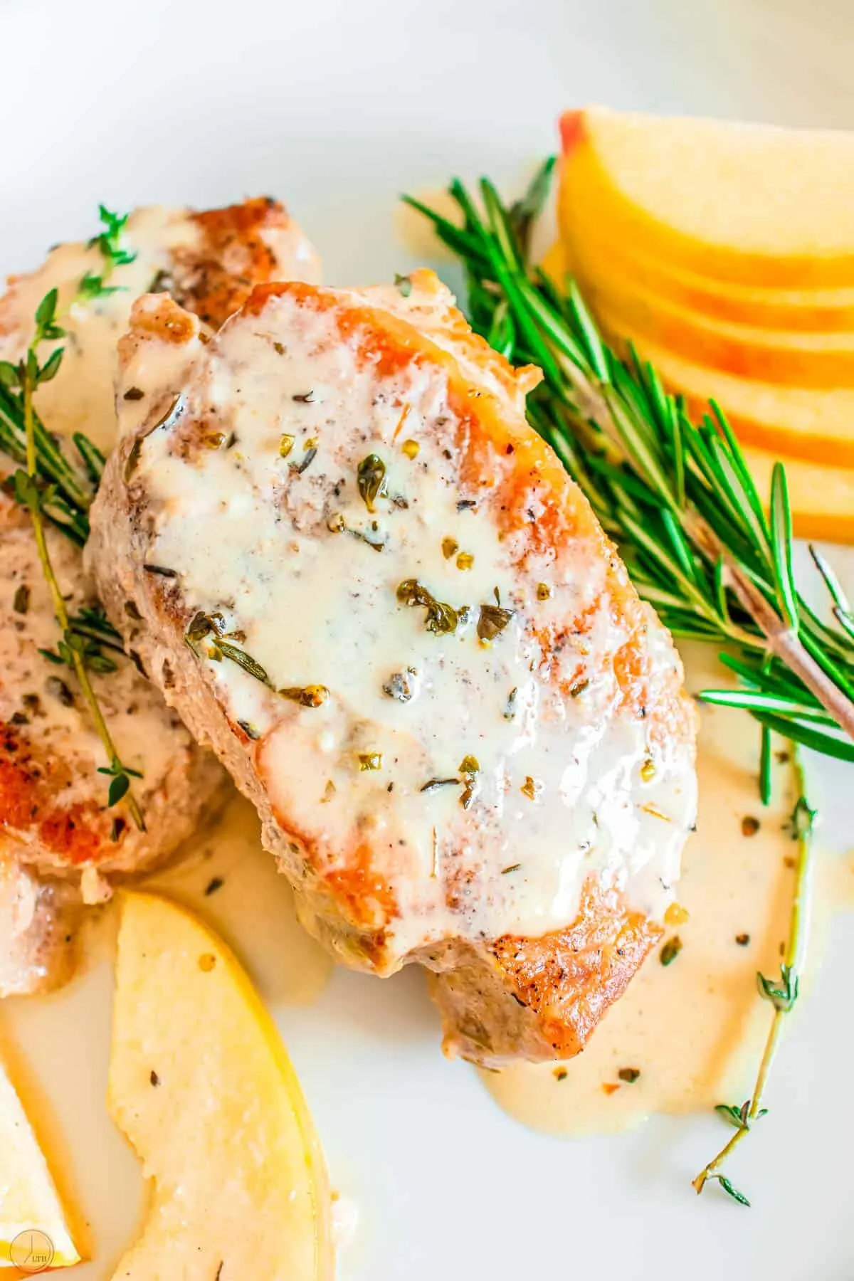 apple cider pork chops with a creamy sauce and apple slices on a plate