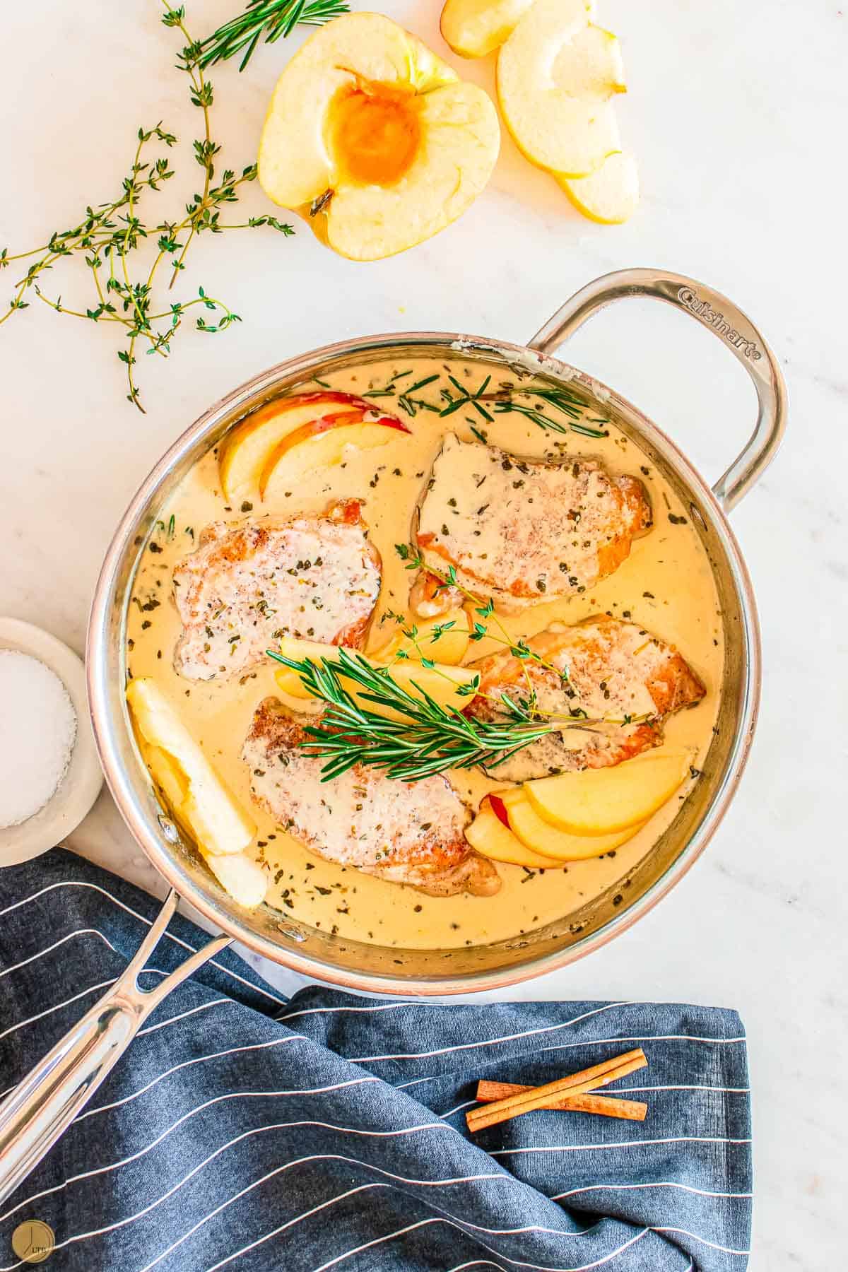 apple cider pork chops in a pan with fresh rosemary
