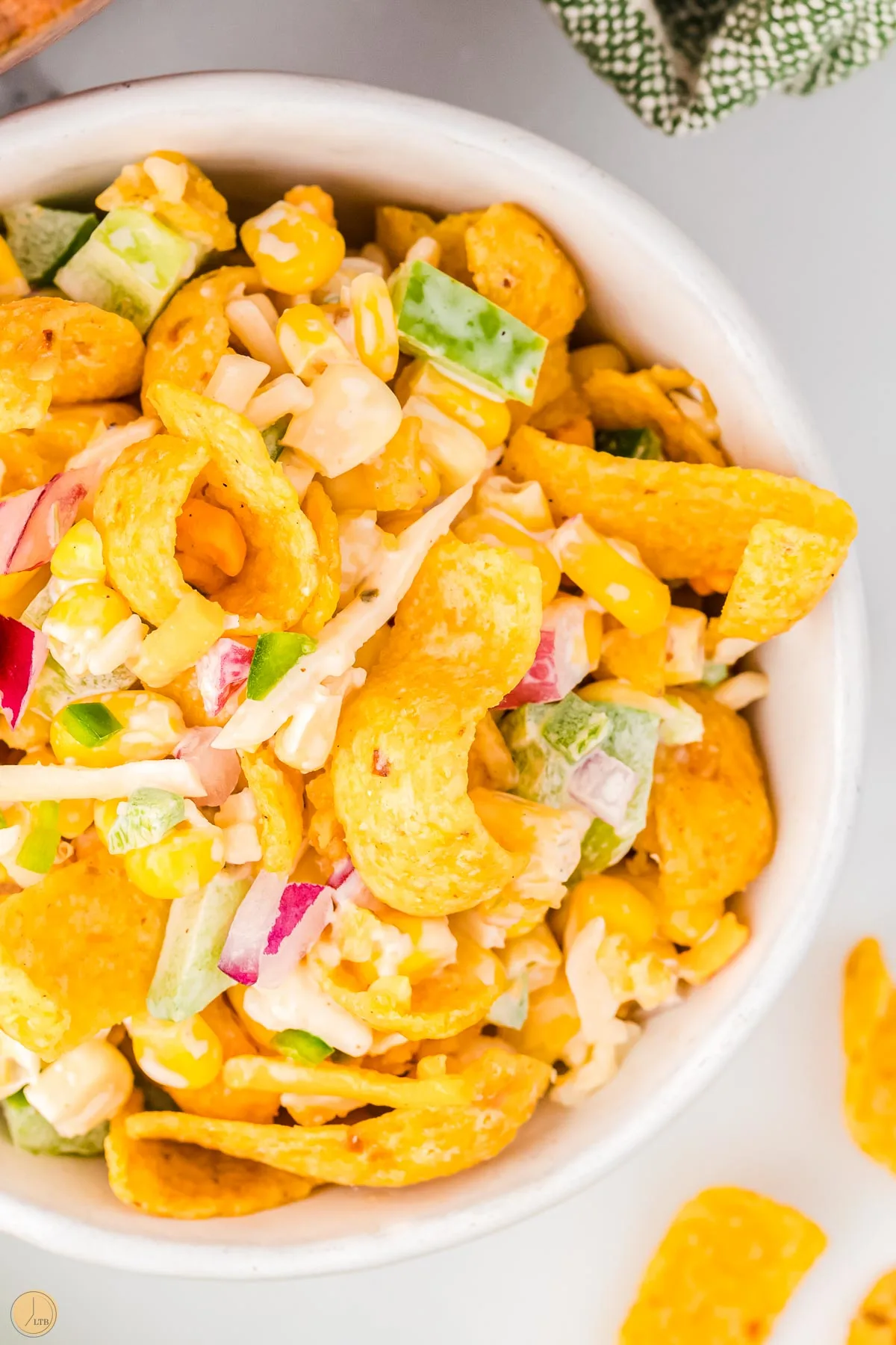 close up of corn chips in a salad with red onion and bell peppers