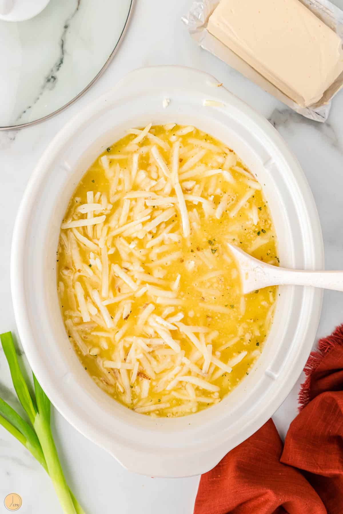 soup being stirred in a crock pot with a white spoon