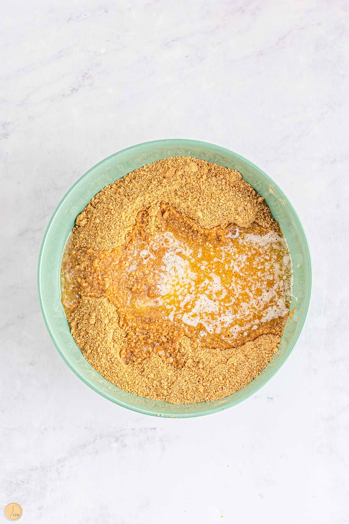 golden brown graham cracker crumbs in a large bowl with melted butter