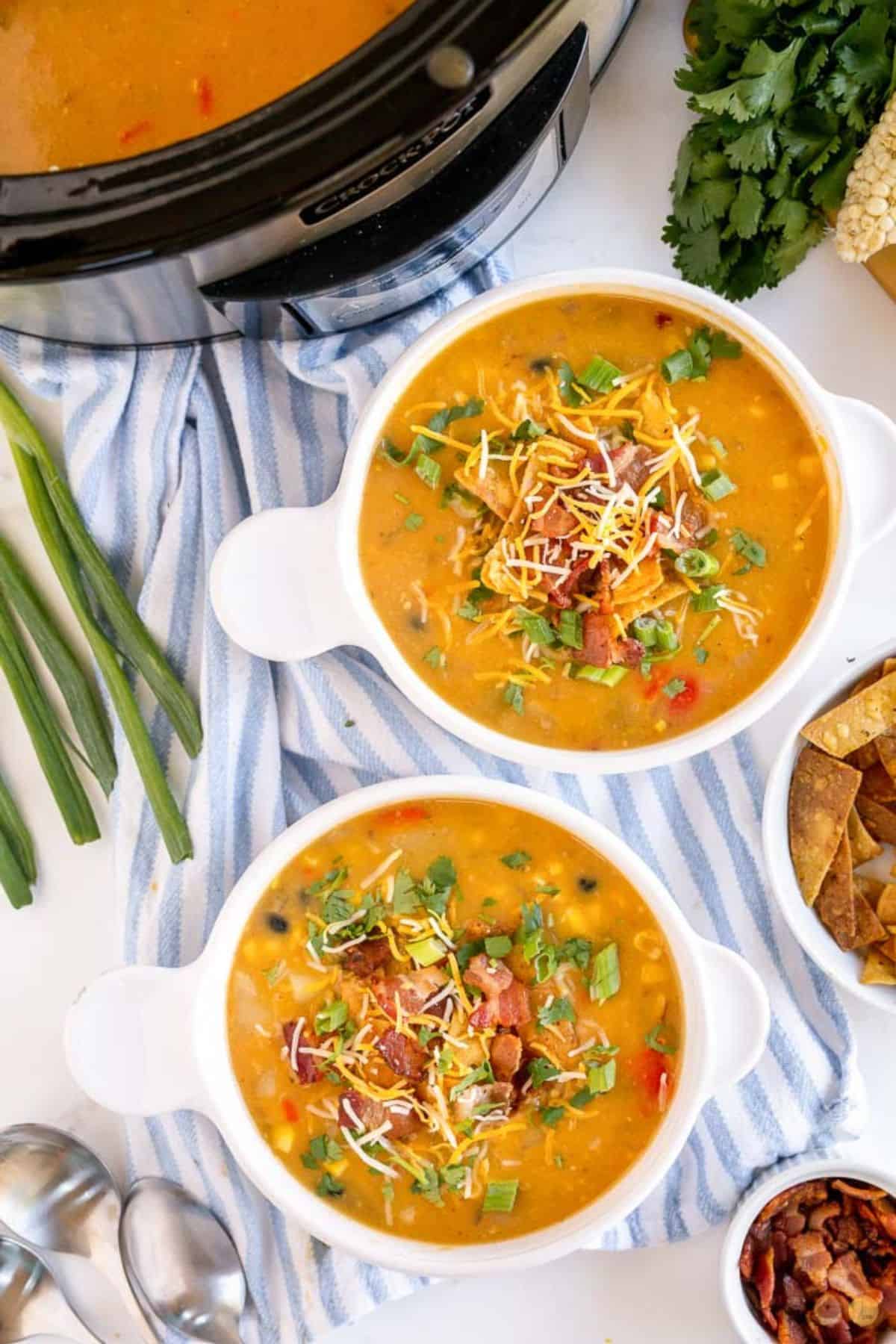 two bowls of soup topped with shredded cheese