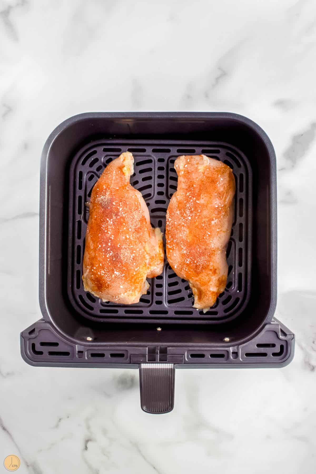 two chicken breast in an air fryer basket