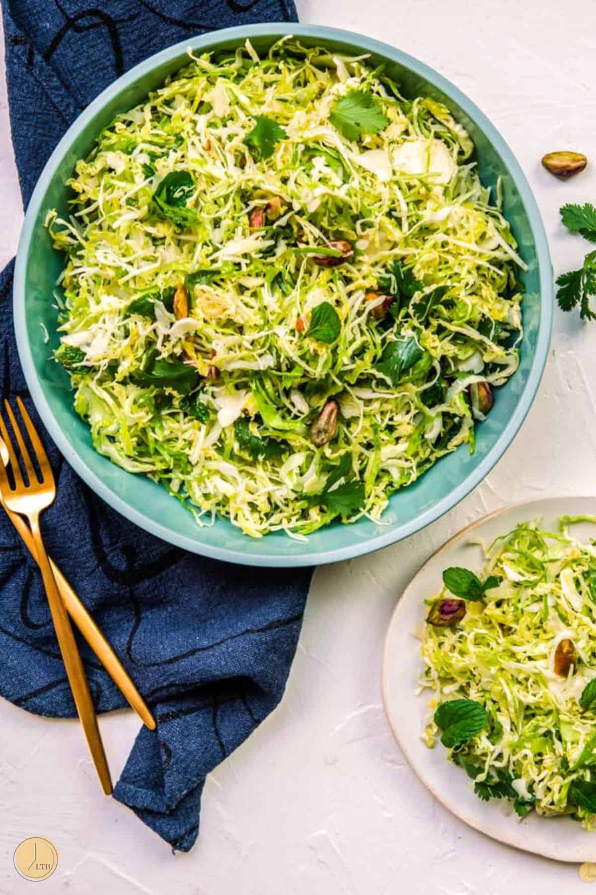 two bowls of slaw with gold forks