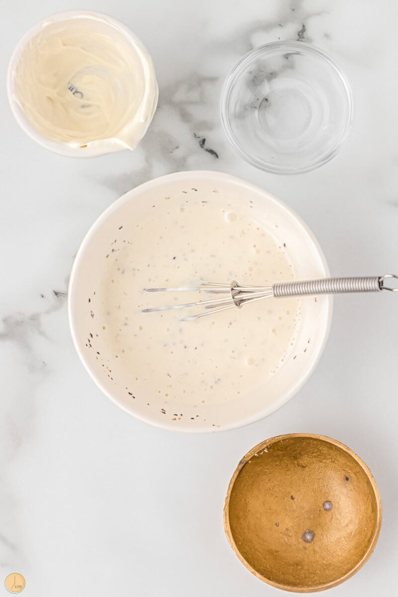 creamy dressing in a white bowl with a whisk