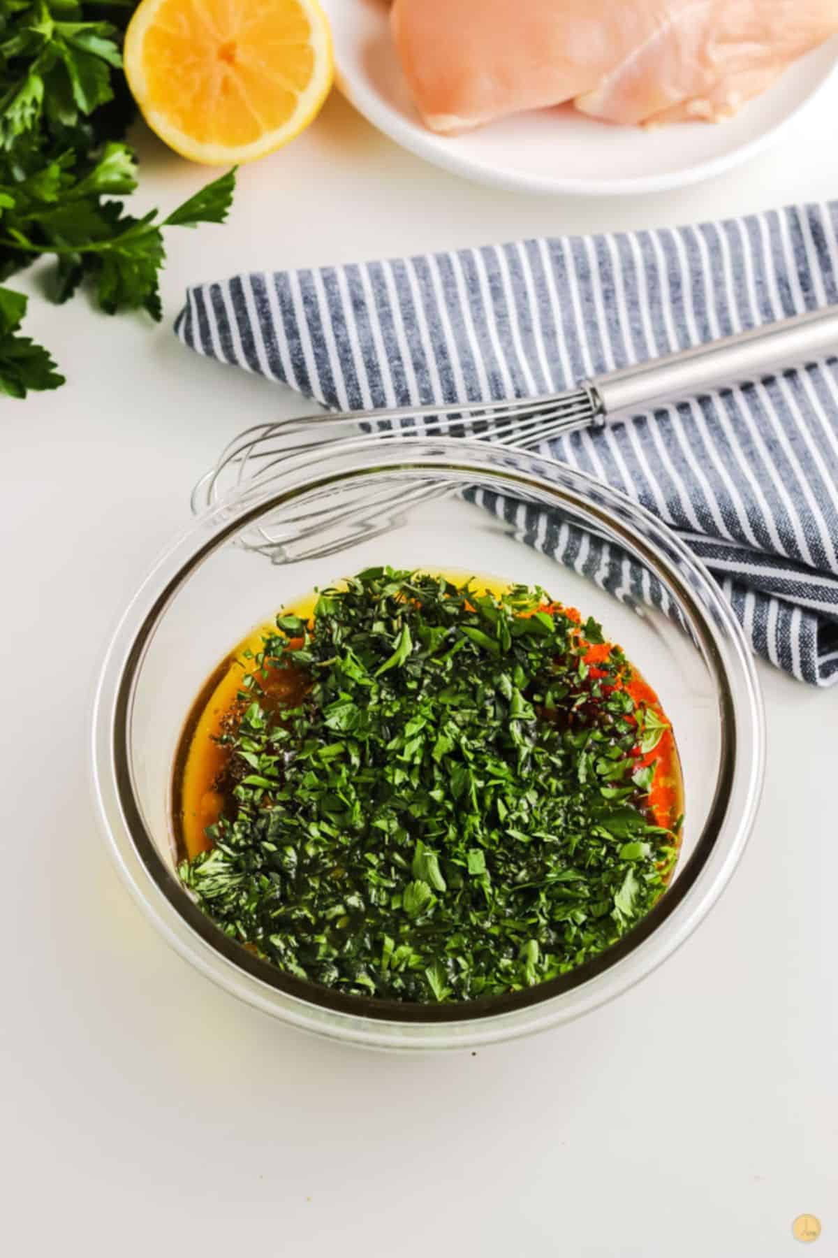 bowl of dressing and fresh herbs with a whisk