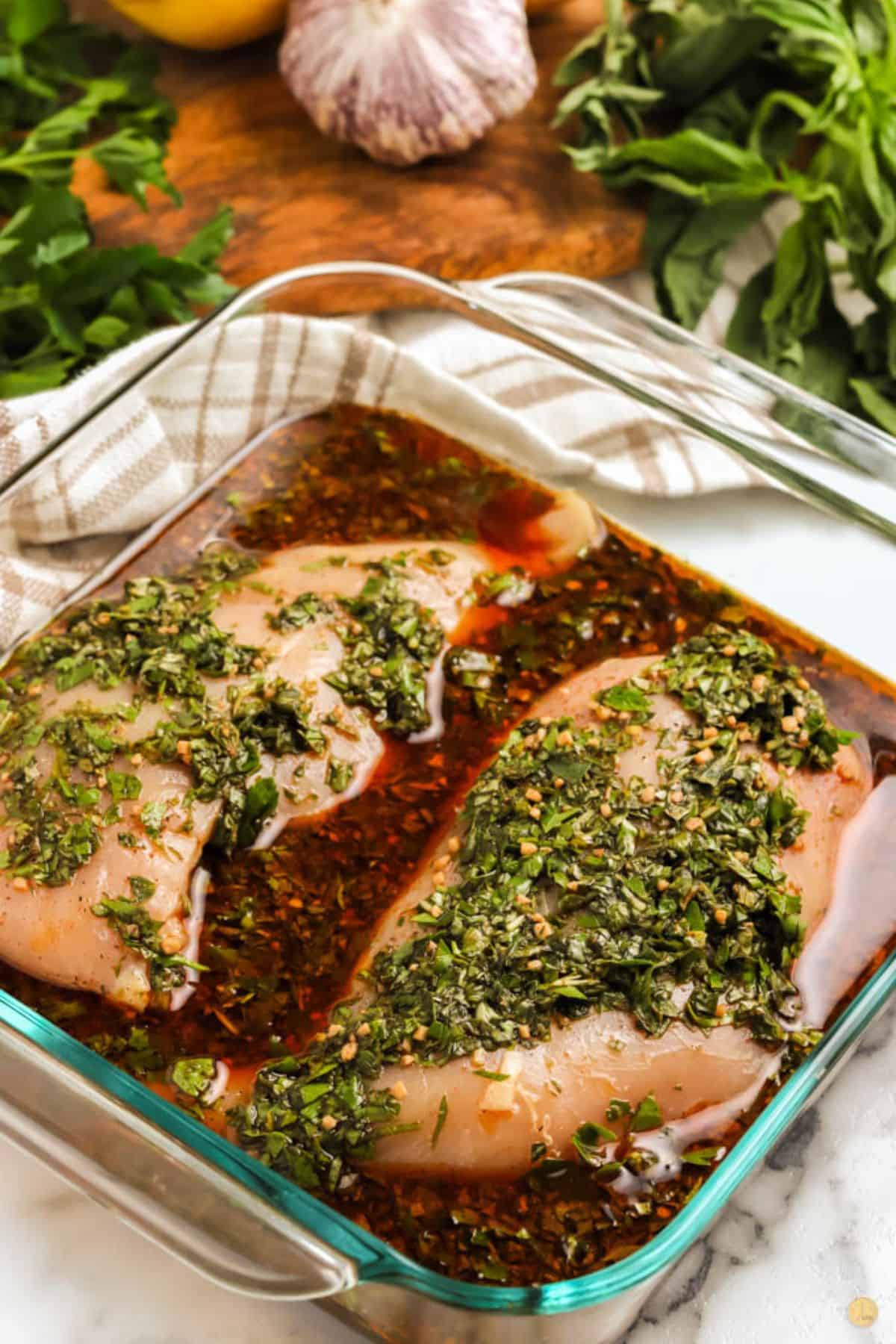 two pieces of chicken marinating in a square dish