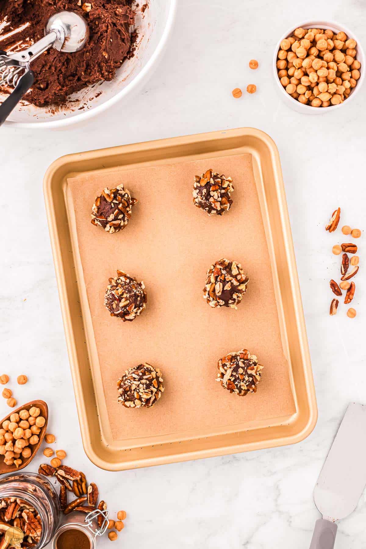 turtle cookie dough balls on a baking sheet