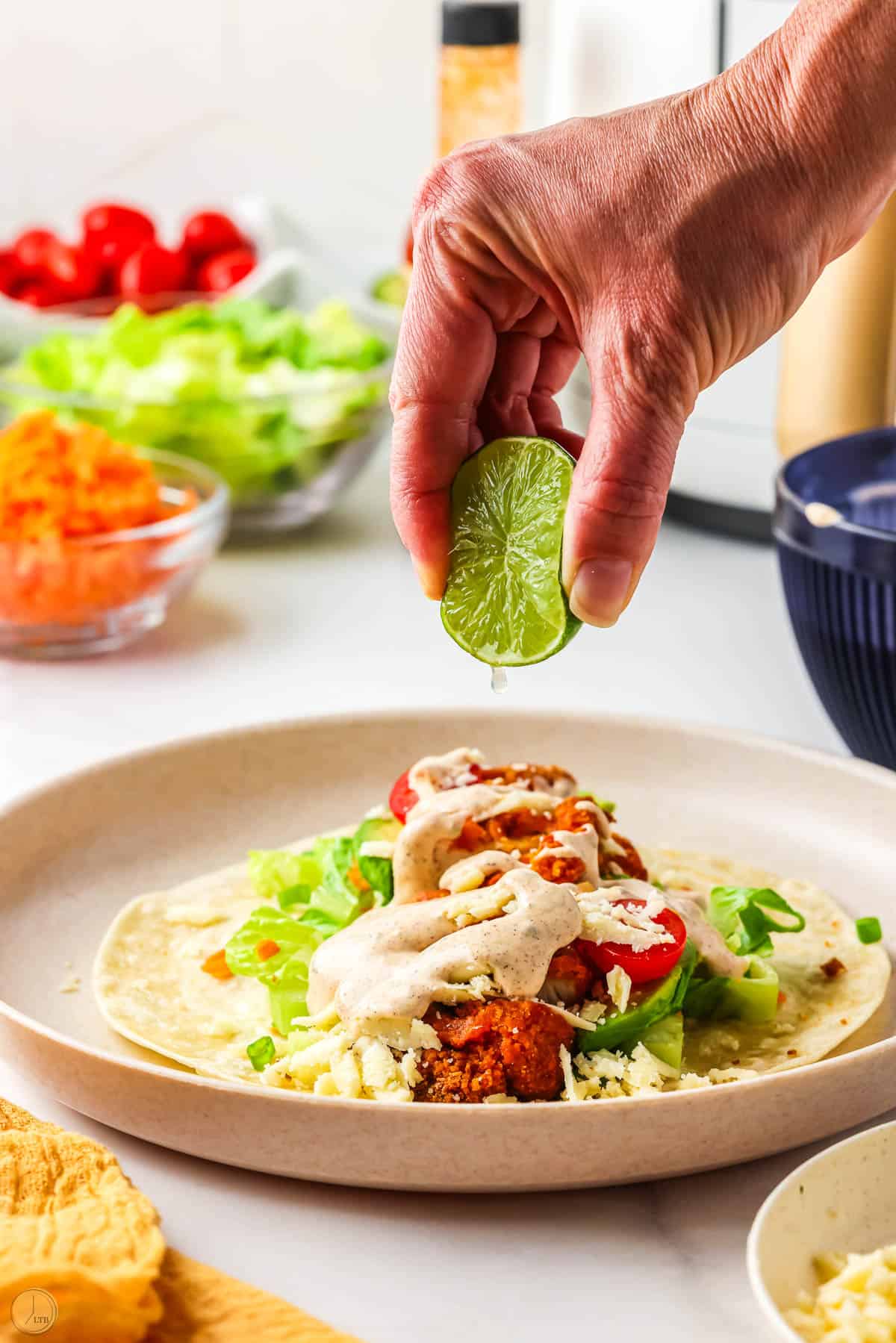 open buffalo chicken wraps with lime being squeezed on it