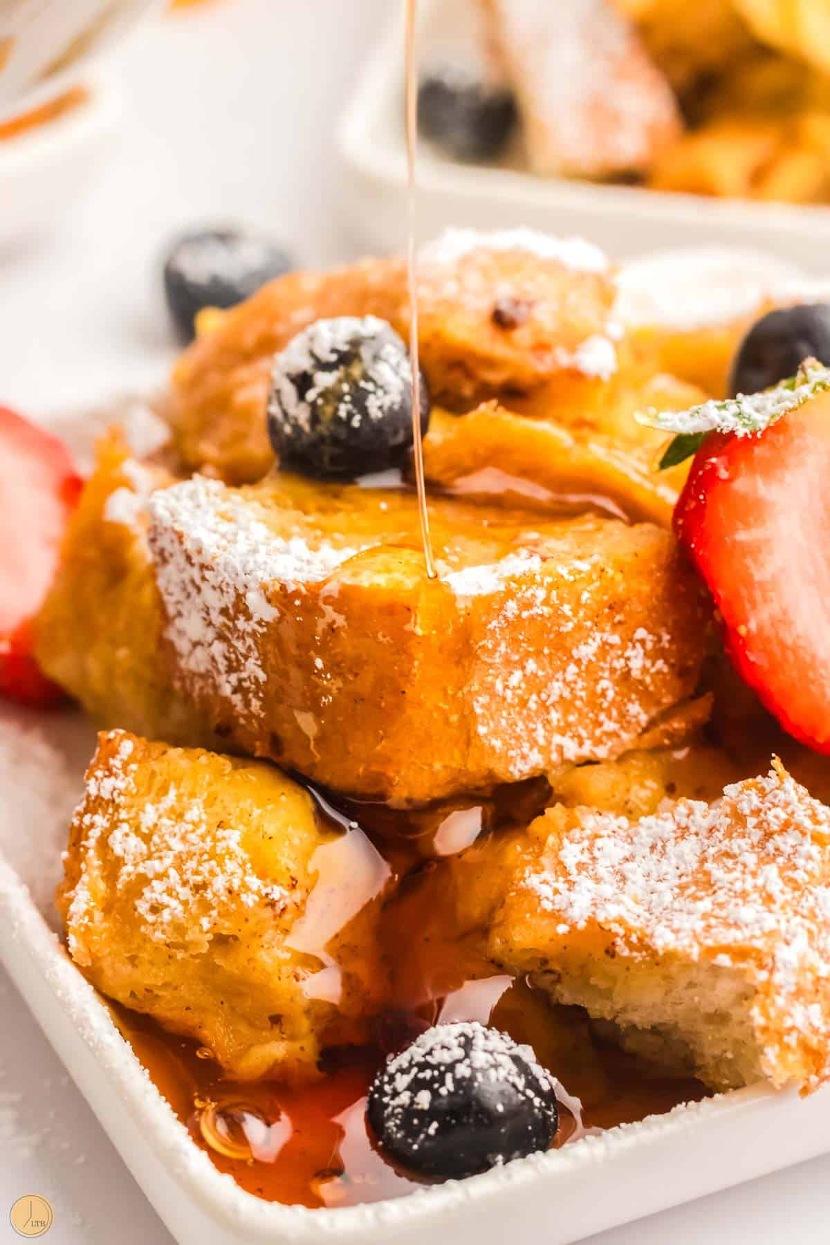 french toast casserole with syrup being poured on it