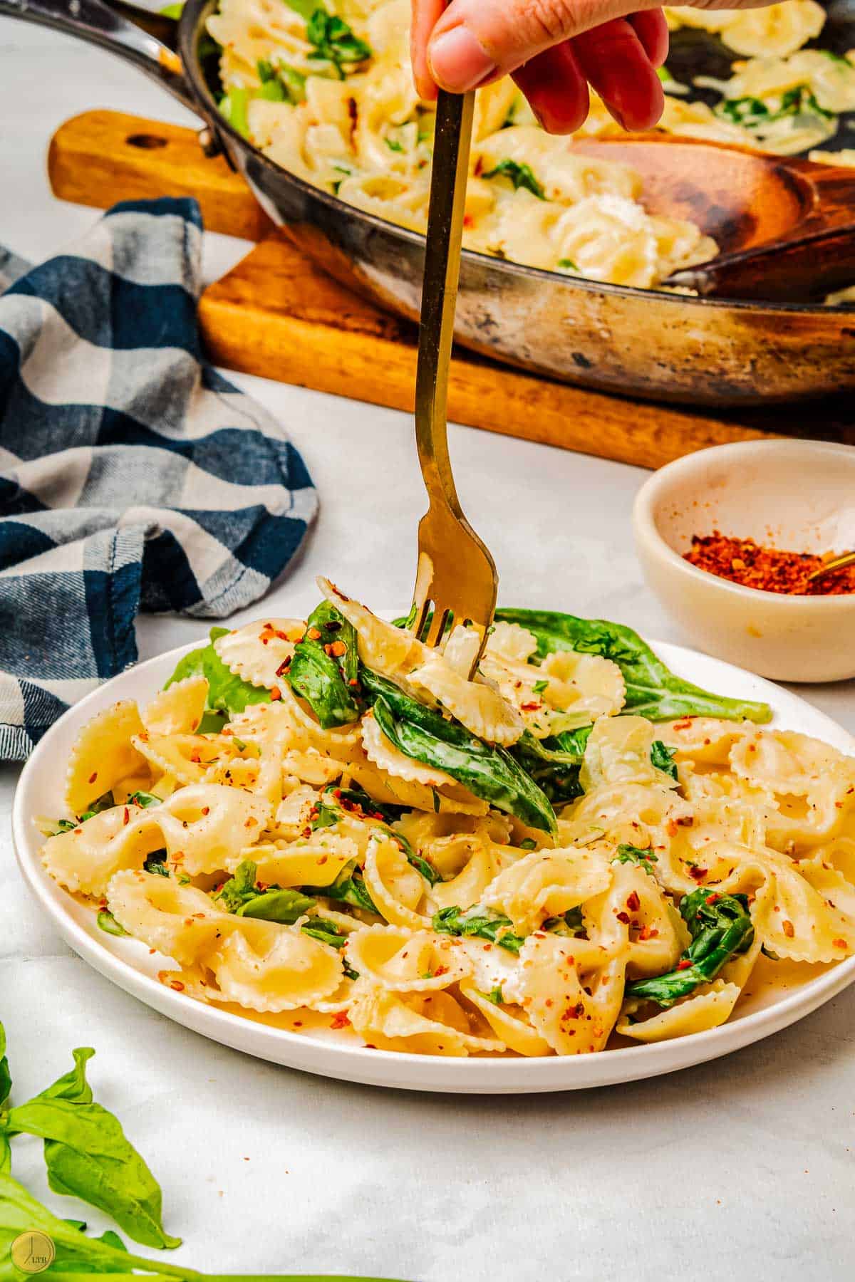 plate of pasta with spinach and sour cream with a fork in it