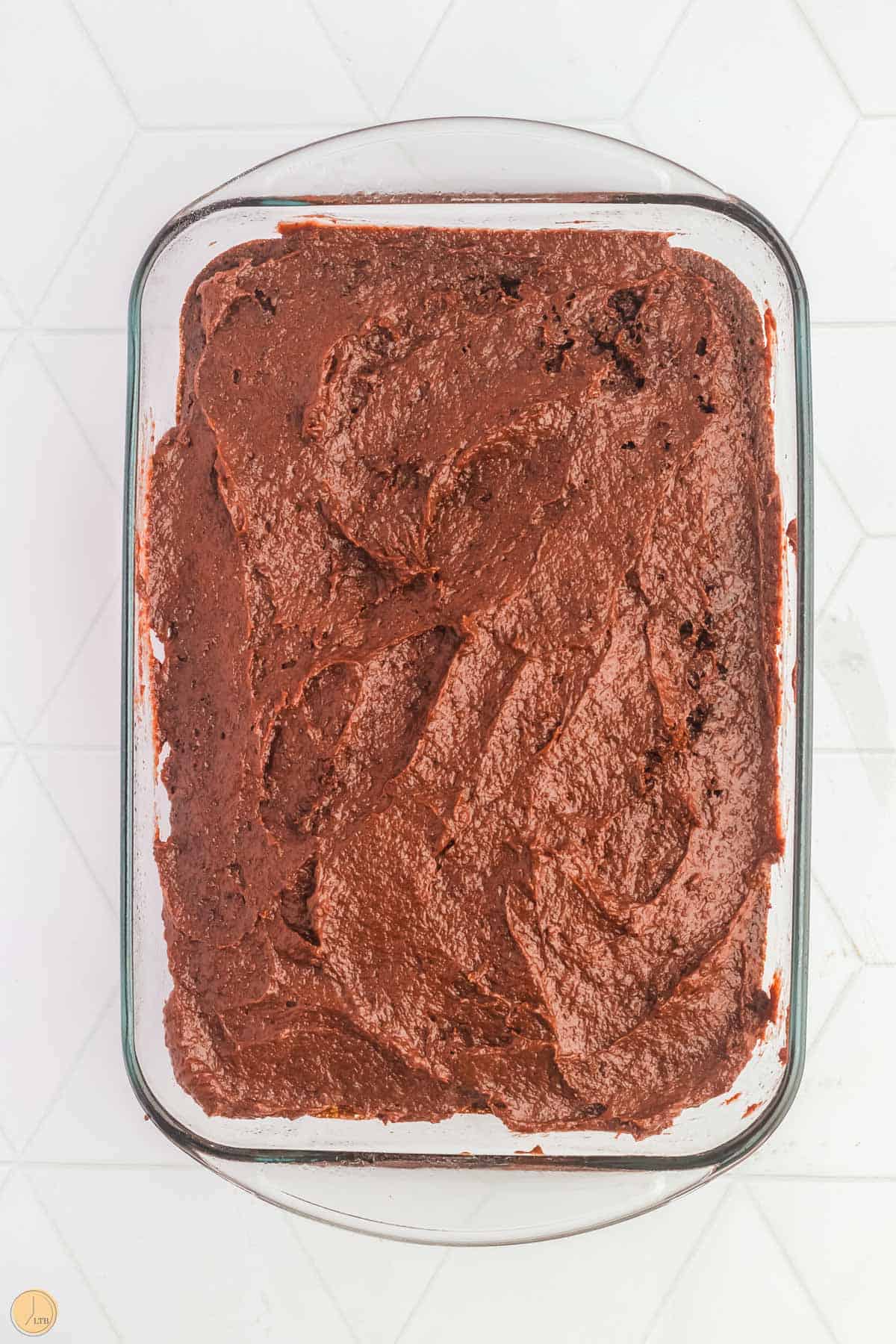 frosted chocolate cake in clear 9x13 pan
