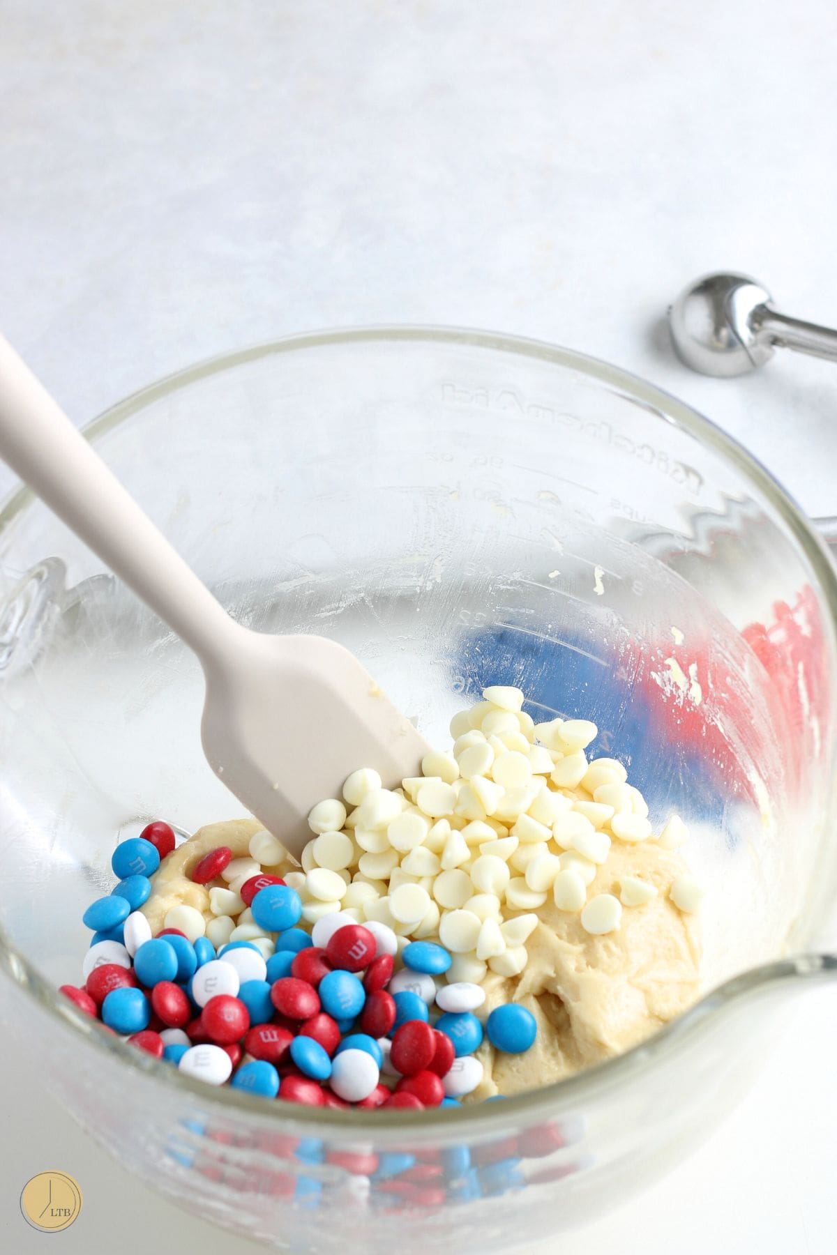 clear bowl with cookie dough and a spatula with candies