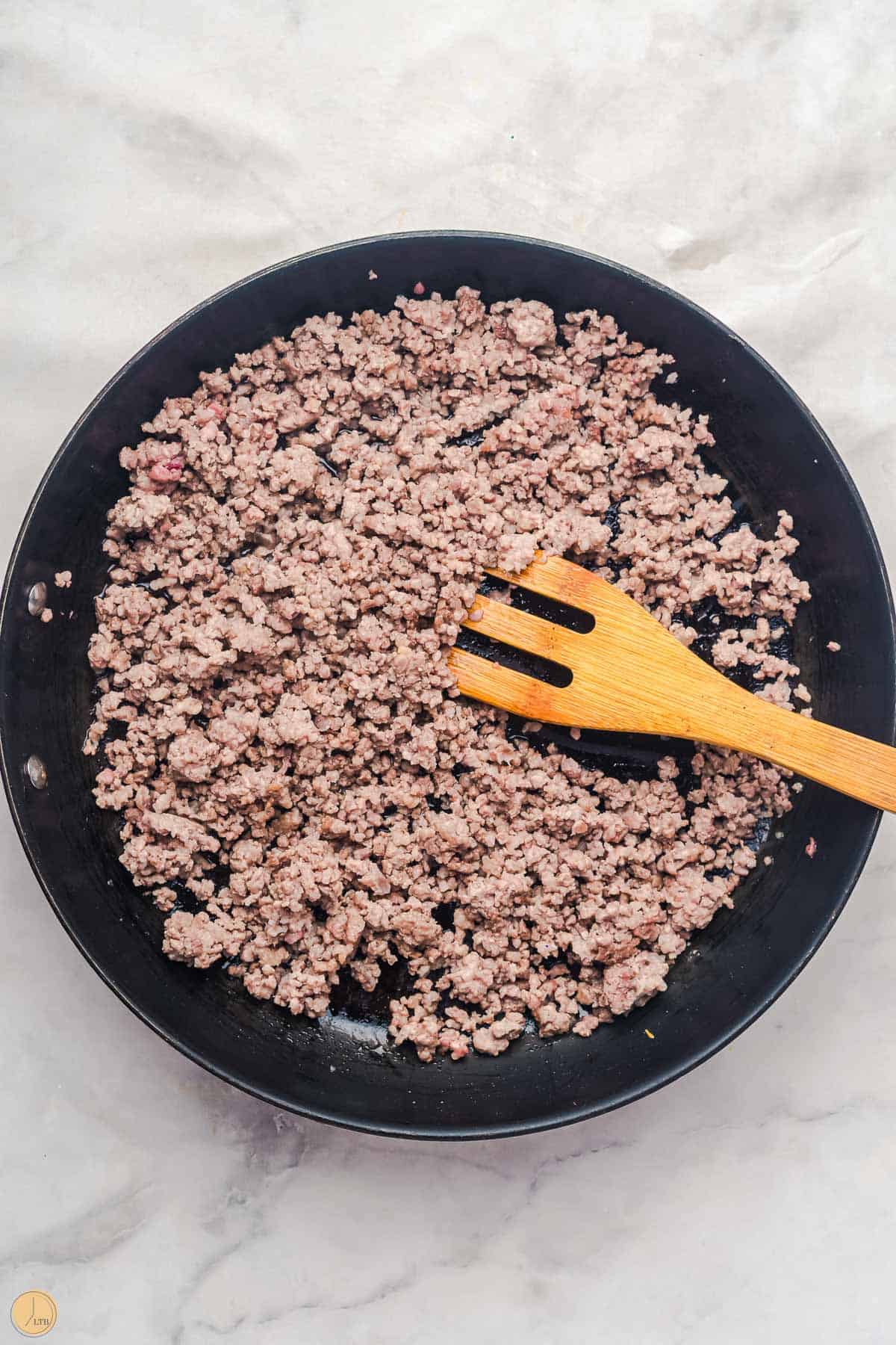 skillet with cooked ground beef a wood spoon