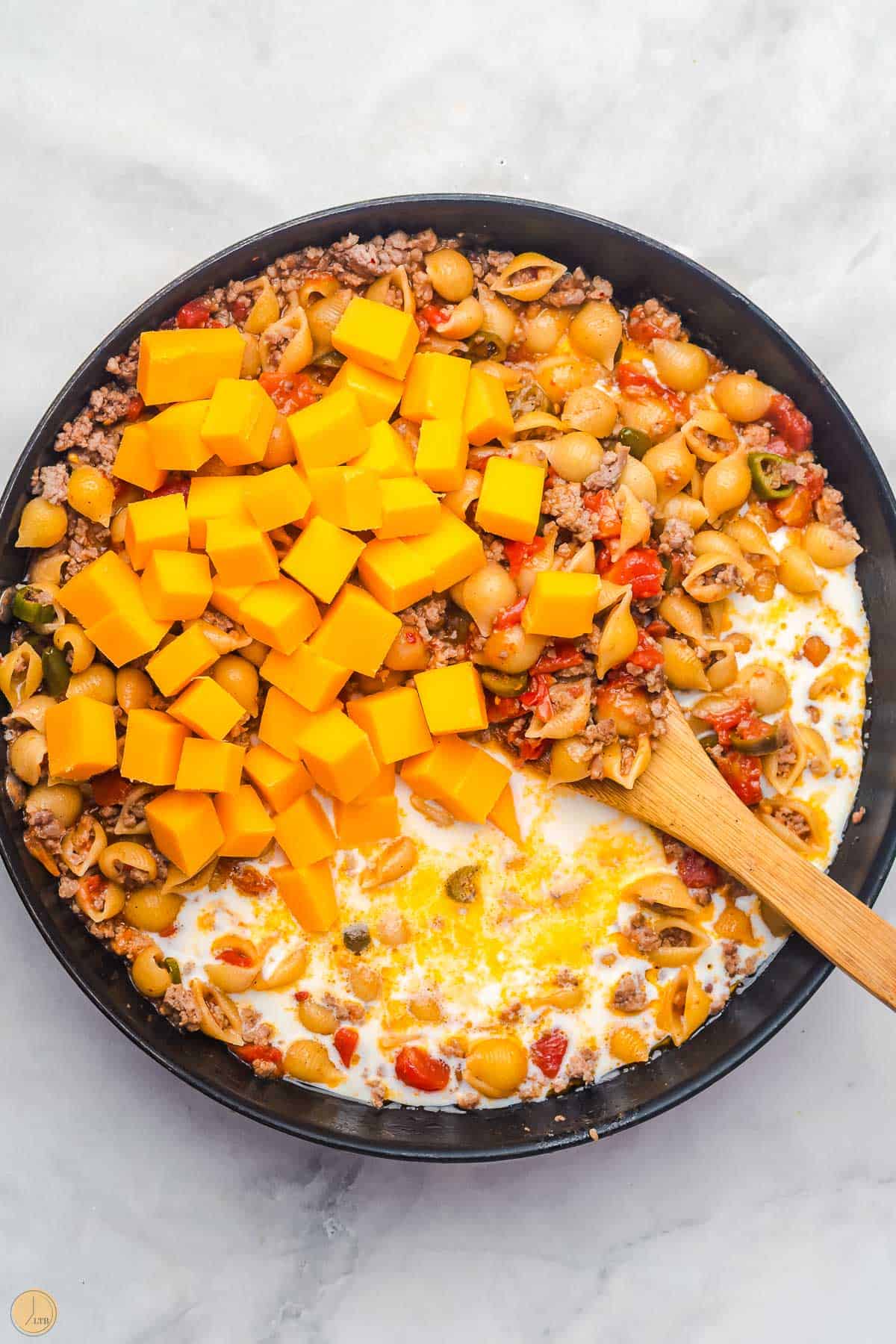 milk and cheese added to a pan of ground beef