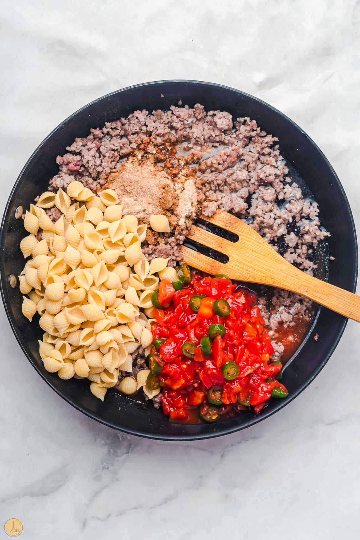 ground beef, pasta shells, and diced tomatoes in a skillet